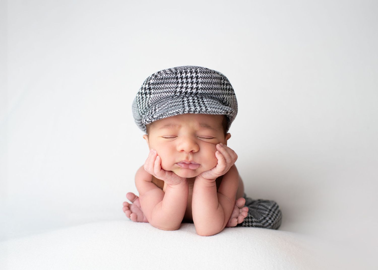 Newborn baby posed with hands under chin during a studio newborn photography session in Linden, New Jersey.