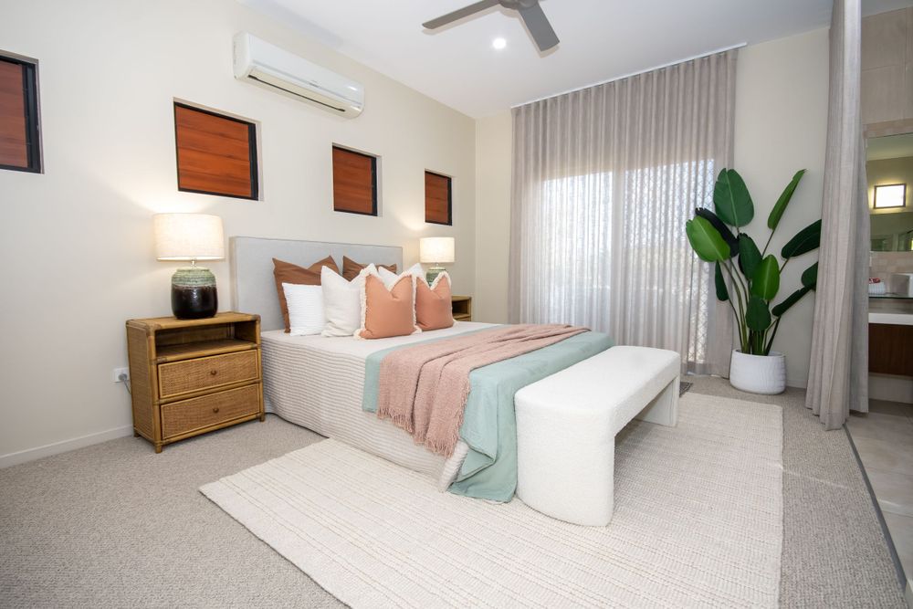 Serene bedroom with coral accents, wooden furniture, and floor-length curtains.