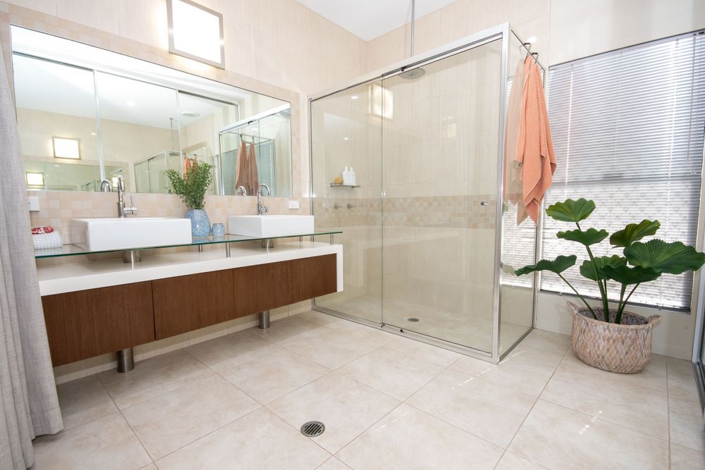 Spa-like bathroom featuring glass shower, double vanity, and potted plants.
