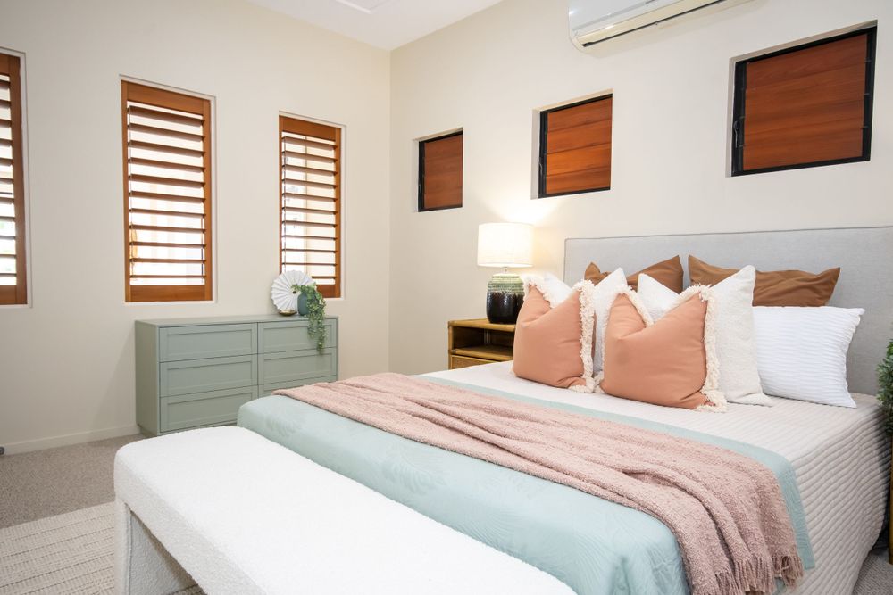 Modern bedroom with mint green dresser and coral accents featuring wooden shutters and plush bedding.