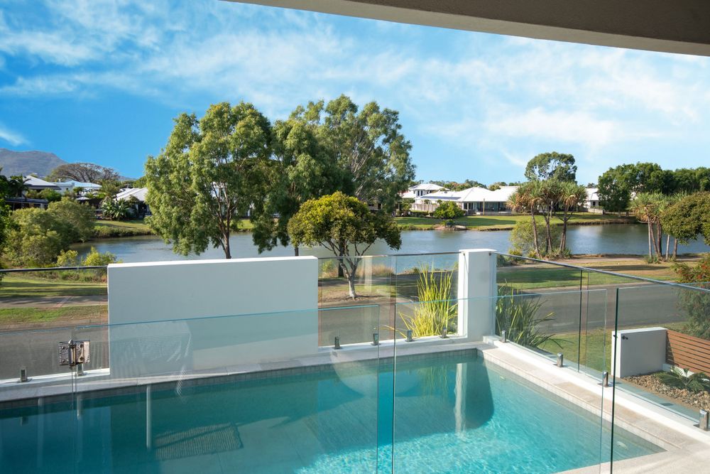 Luxurious outdoor pool area with glass barriers overlooking a scenic landscape and trees.