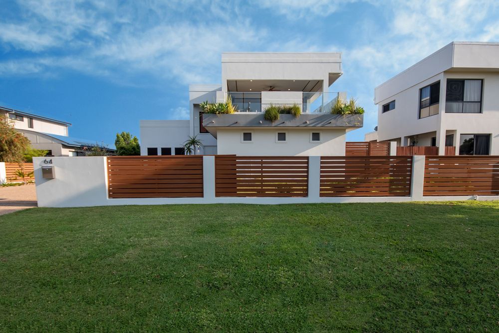 Modern white house with wooden fence paneling and manicured green lawn.