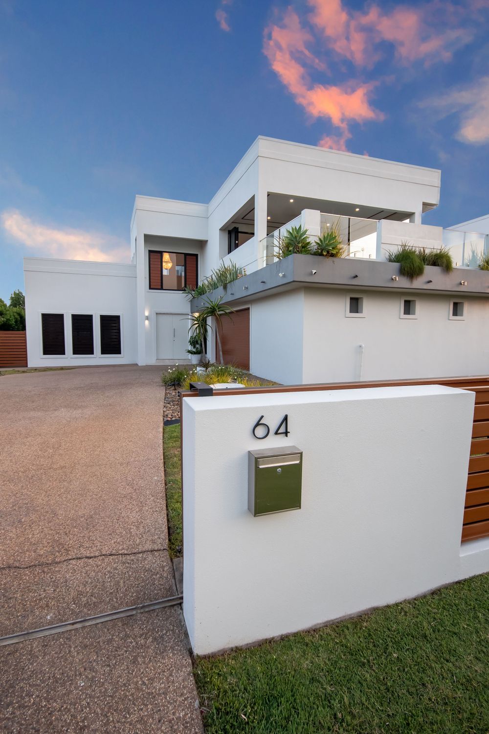 Contemporary white house with number 64 on entrance wall captured during sunset.