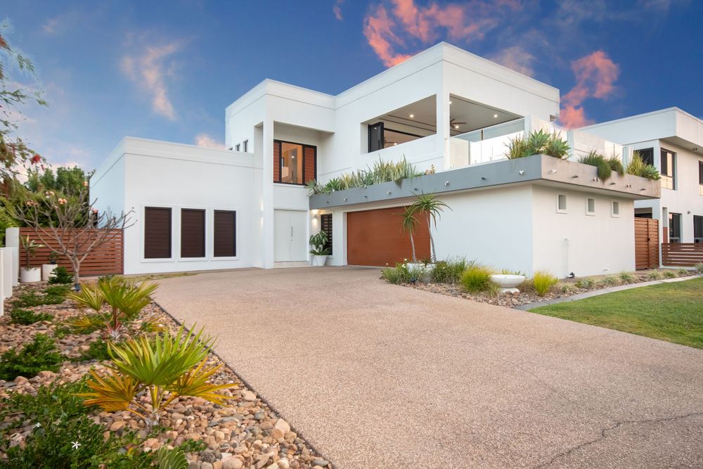 Contemporary white house with exposed aggregate driveway and modern landscaping.