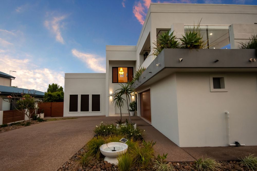Modern white house with garden features photographed at sunset with warm lighting.
