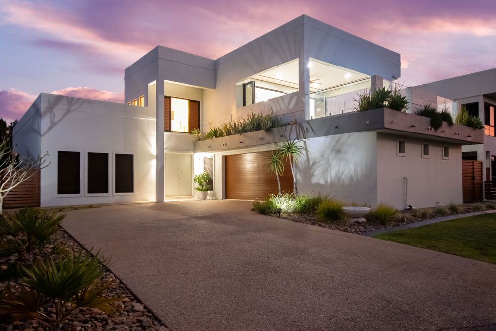 Luxurious modern home exterior with dramatic lighting against purple sunset sky.