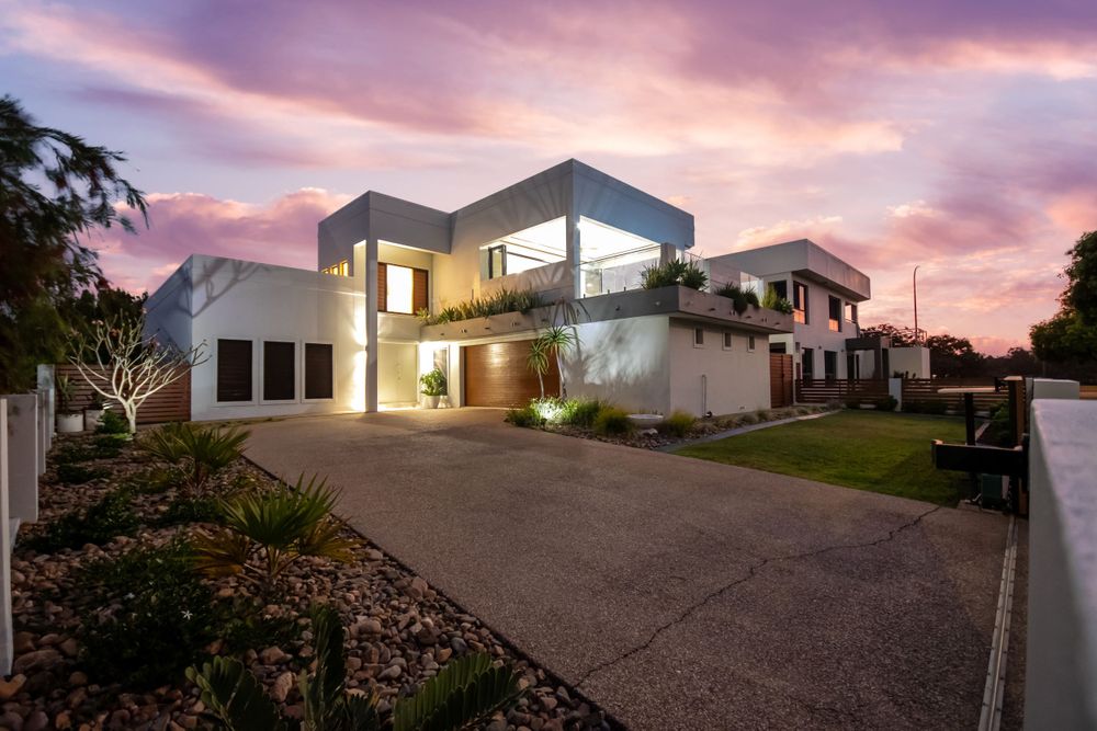 Modern luxury home exterior with dramatic sunset sky and sleek architectural design.