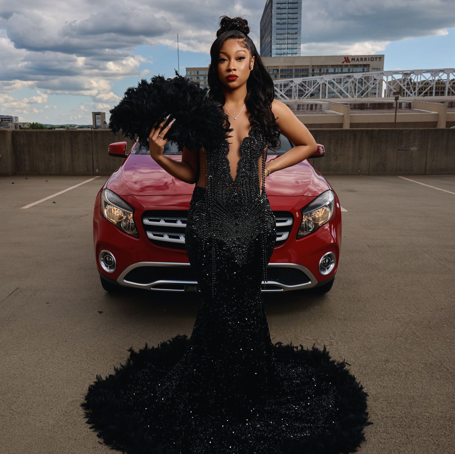 Glamorous black sequin gown photoshoot with red luxury car on urban rooftop.