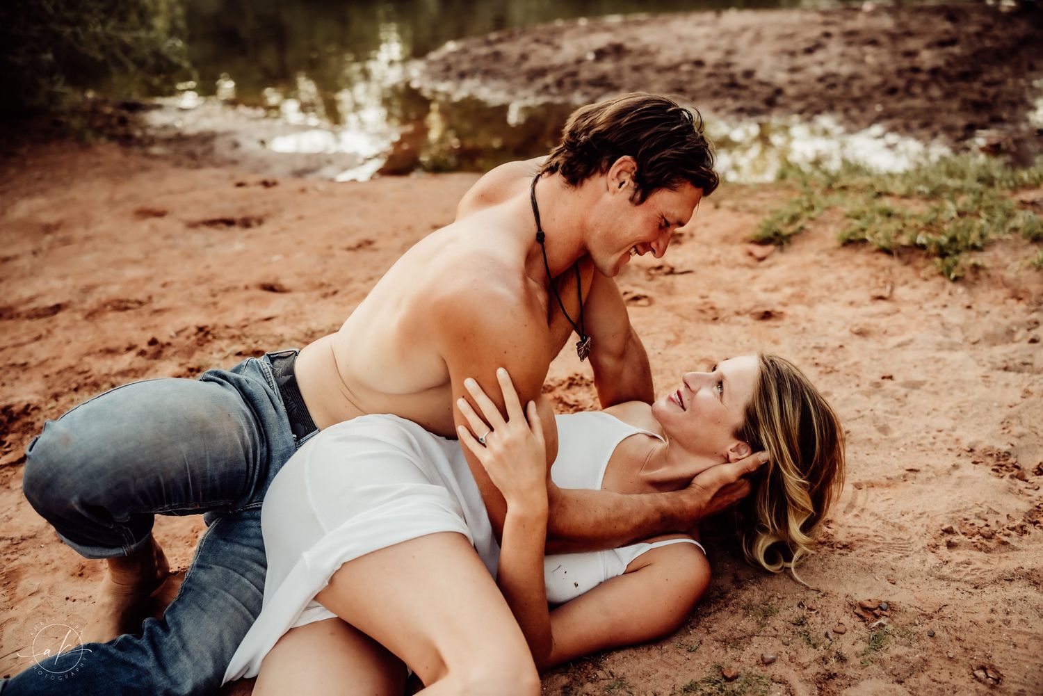 Couple embracing intimately on Sedona red desert rocks during sunset photoshoot.
