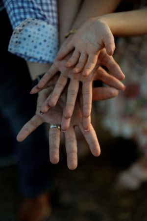 Close-up shot of hands stacked on top of each other against a blurred background. Family Photography