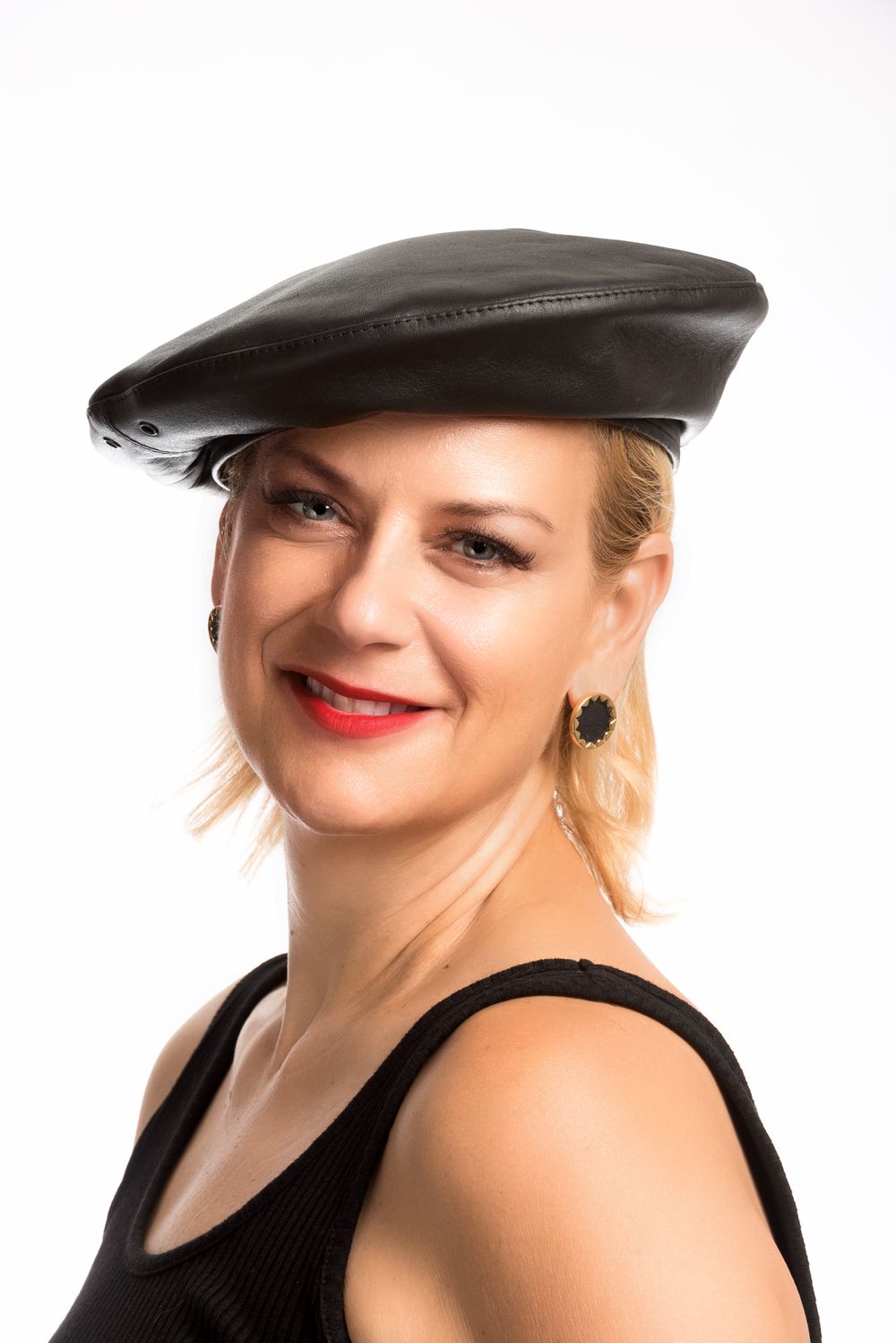 Portrait of woman wearing black leather beret and sleeveless top with red lipstick.