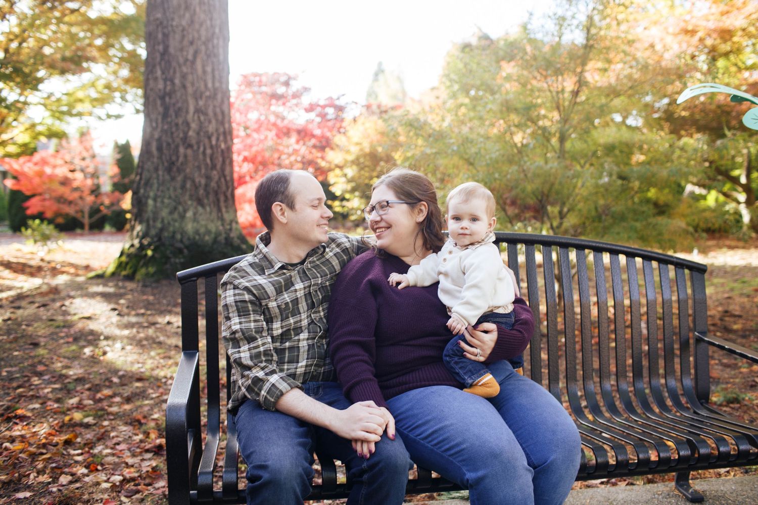 A family sits on a bench sharing a candid moment during their family photo session in Everett WA