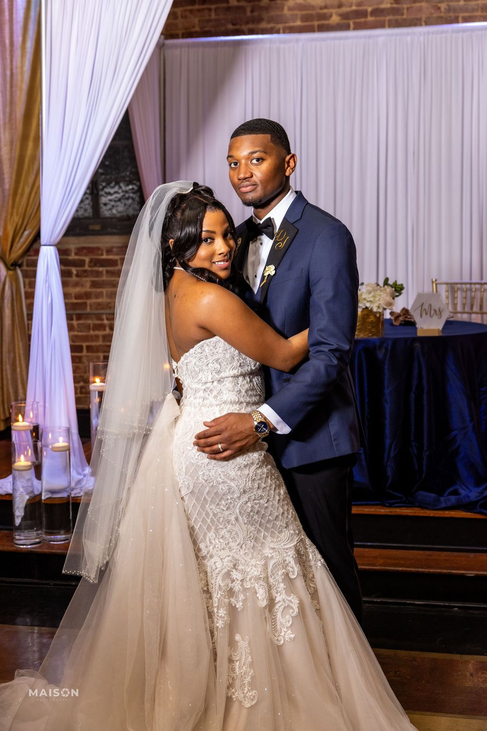 Romantic wedding couple shares intimate dance moments in an elegantly draped ballroom with exposed brick walls.
