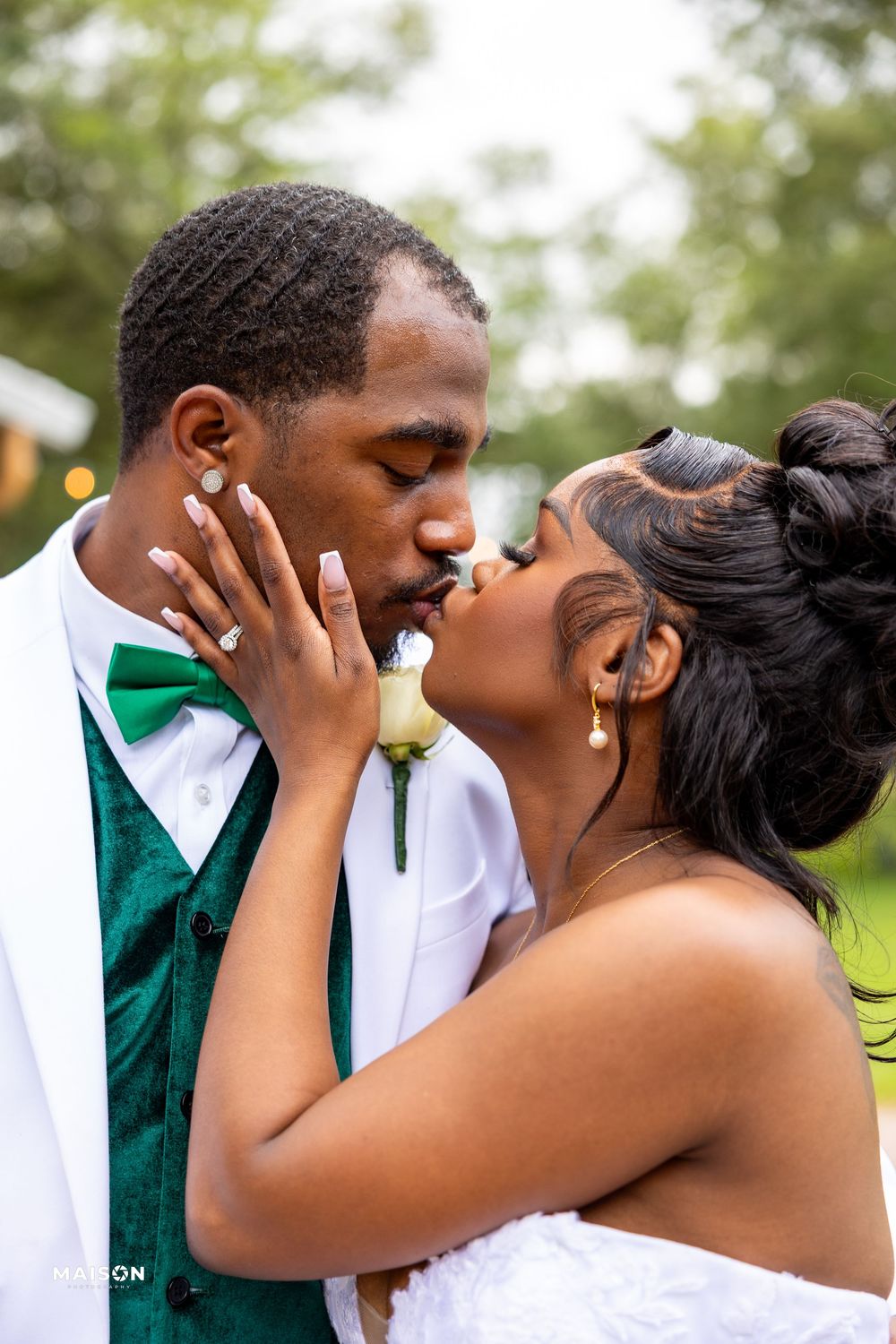 Romantic sequence of a couple sharing tender kisses outdoors, with the groom in emerald green accents.