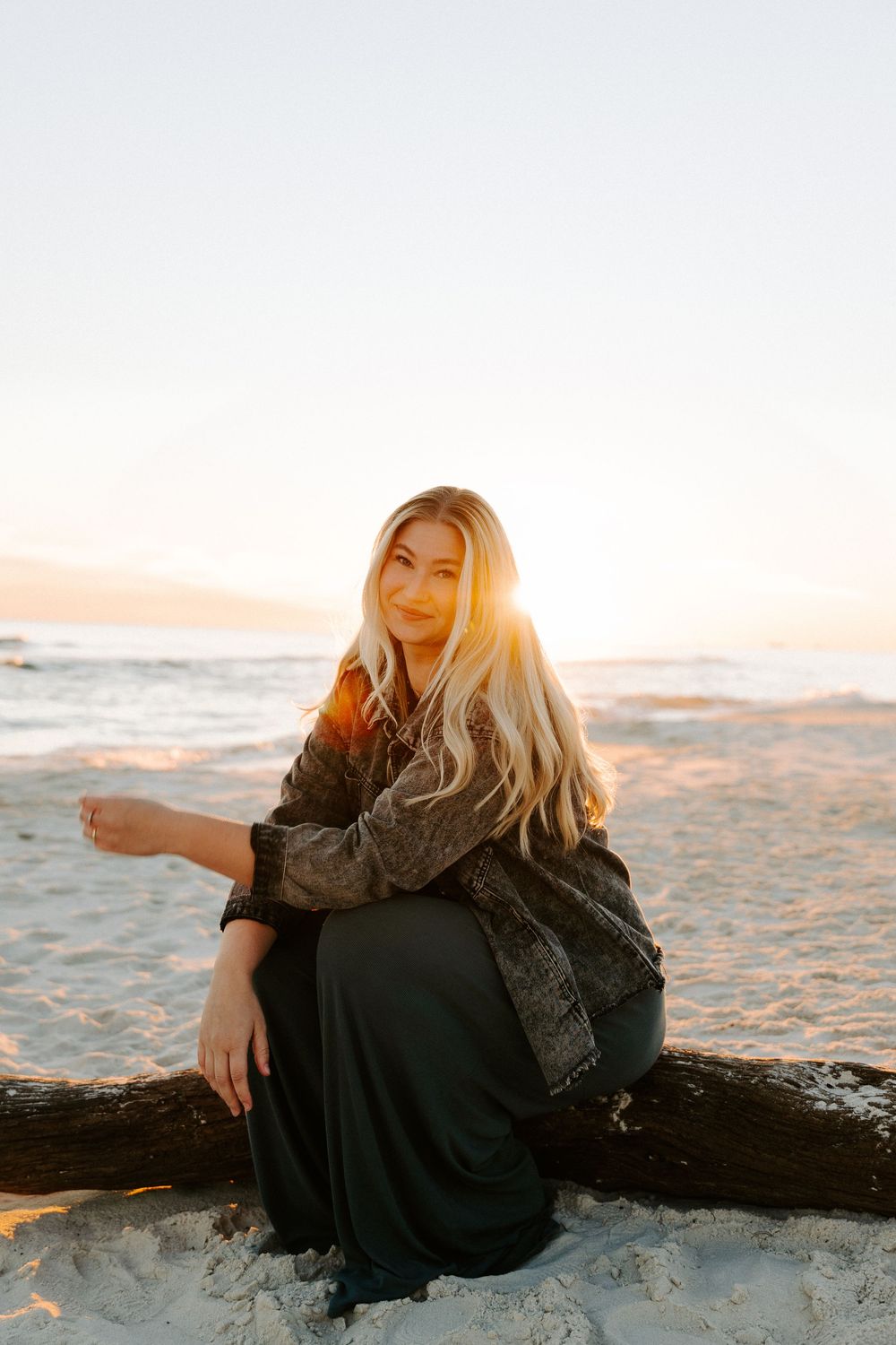 A person in a black dress sits on a sandy beach at sunset, captured in a series of warm-toned photos.