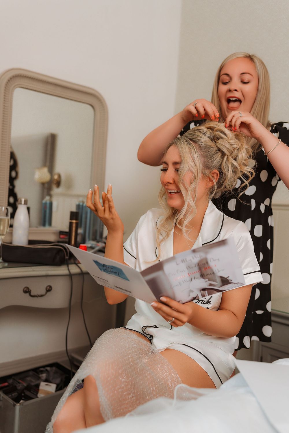 Two people sharing a lighthearted moment while reading a magazine during a hair styling session.