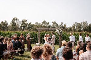 Outdoor wedding ceremony in a field with guests watching the celebration.