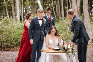 Wedding ceremony signing moment outdoors with attendants in formal attire.