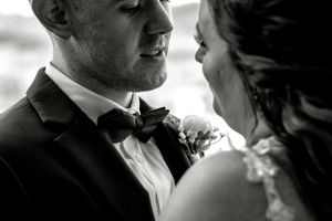 Intimate black and white close-up of couple sharing tender moment in formal wedding attire.