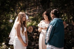 Outdoor ceremony moment with wedding party in natural sunlit setting.