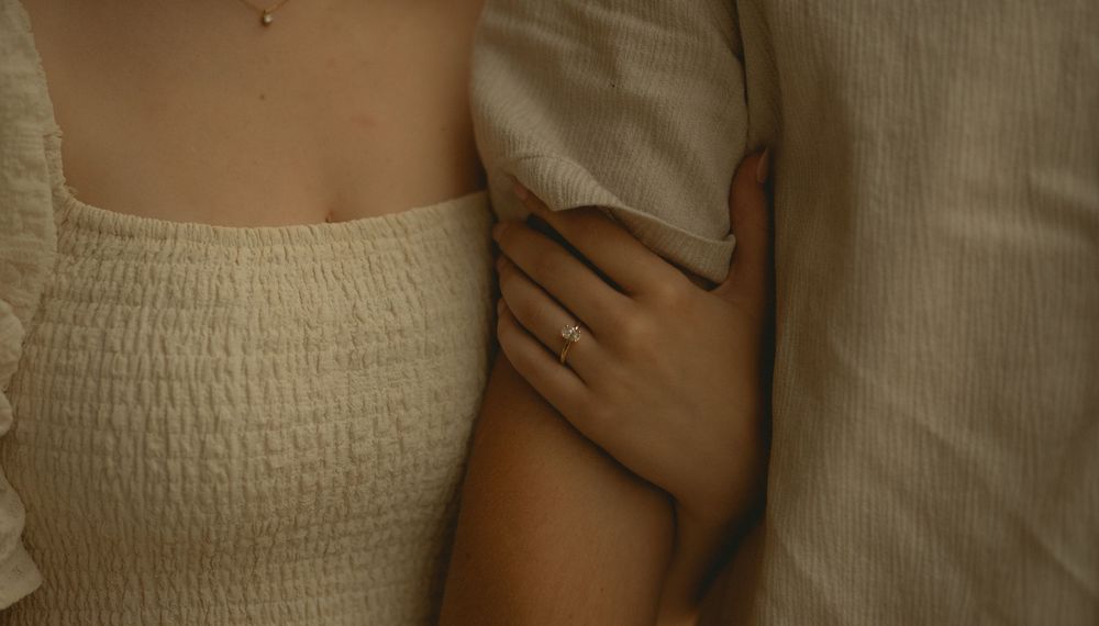 Close-up of a woman in cream smocked top with a hand gently resting on her arm.