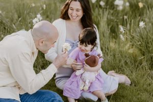 A joyful family moment together outdoors in a grassy field on a sunny day.