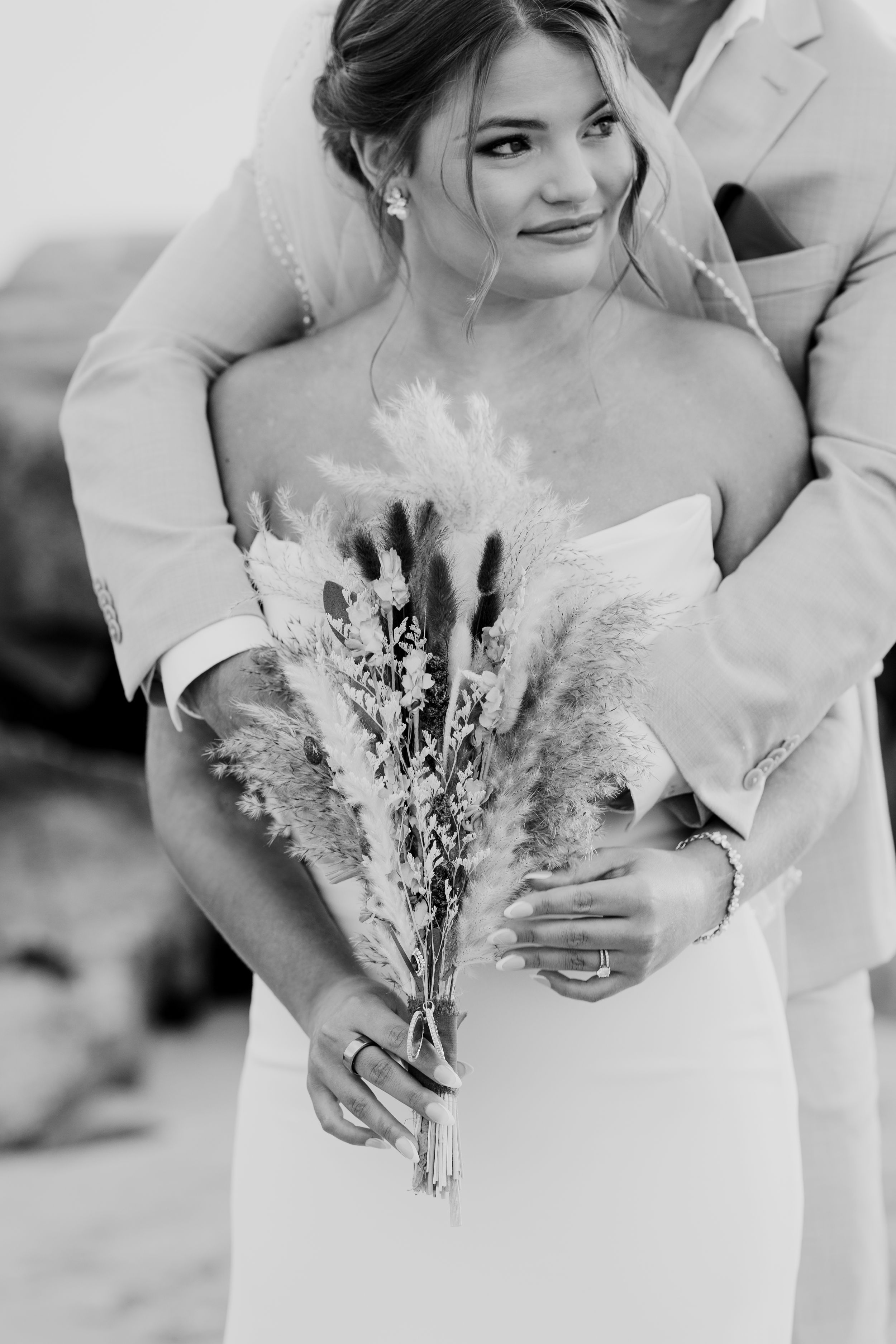 Black and white close-up of bride holding dried flower bouquet.