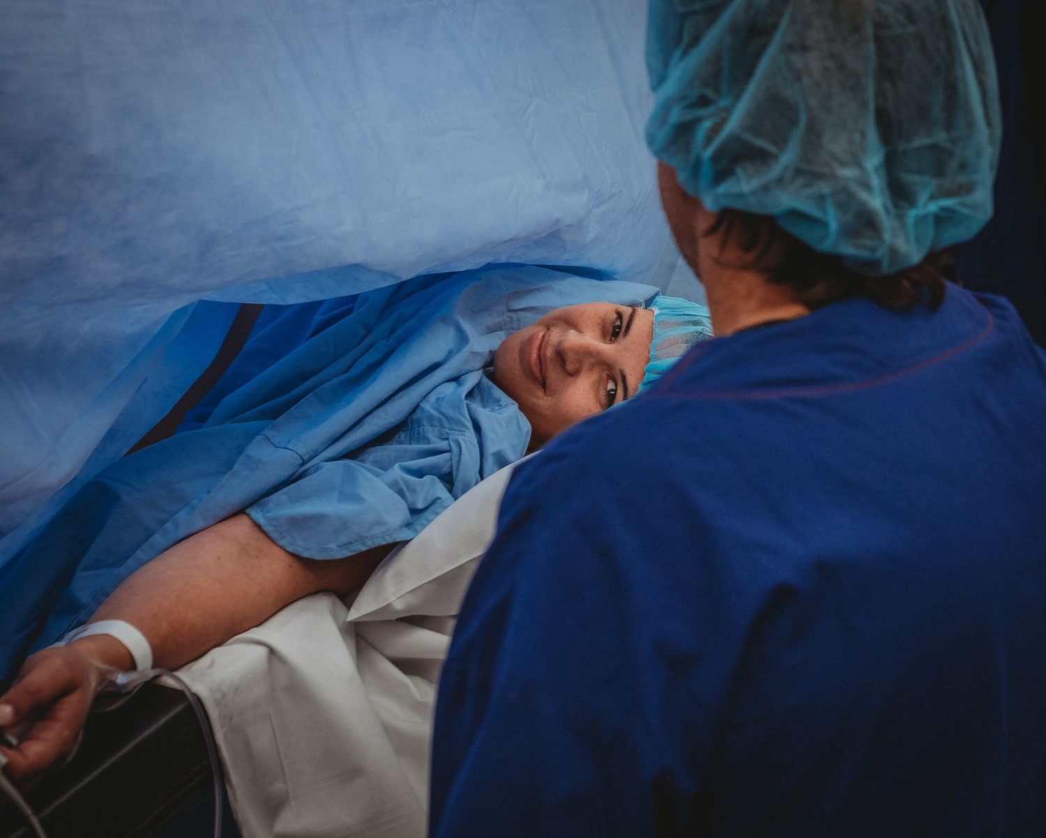 Medical professionals in surgical attire during hospital procedure.
