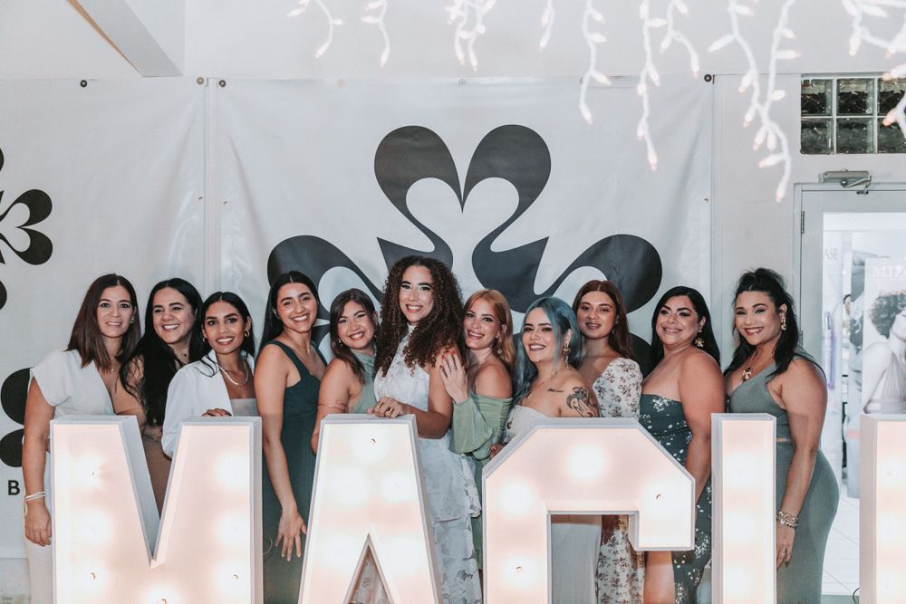 Group photo with large illuminated letters and heart decorations in background.