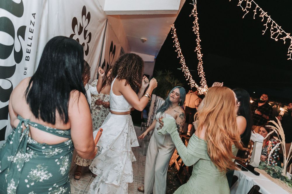 People dancing and celebrating at an event with string lights and decorations.