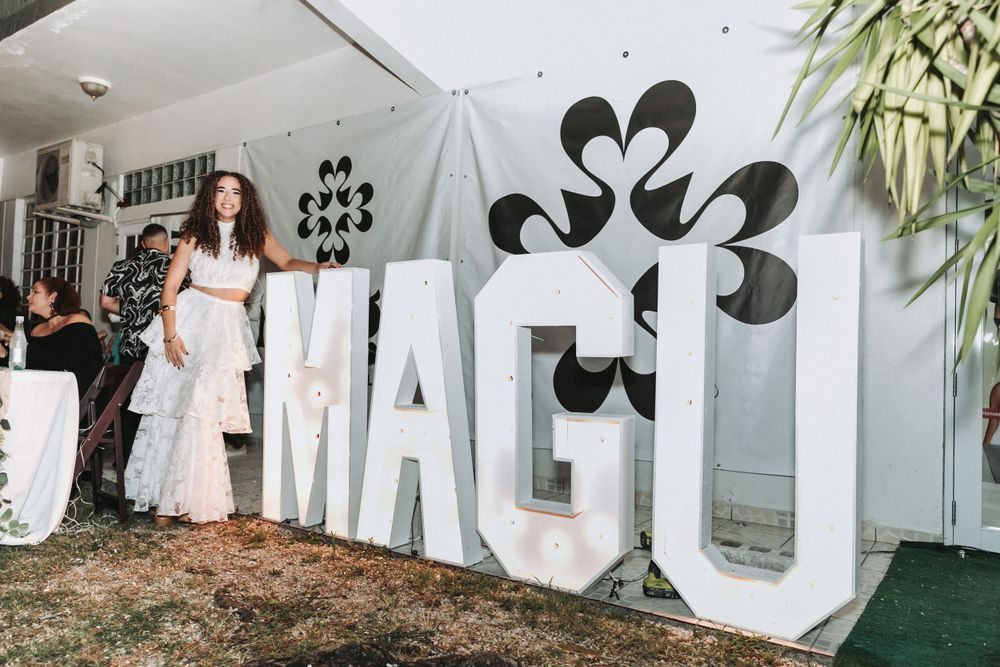 Large white decorative letters spell out MAGU against wall with heart designs.