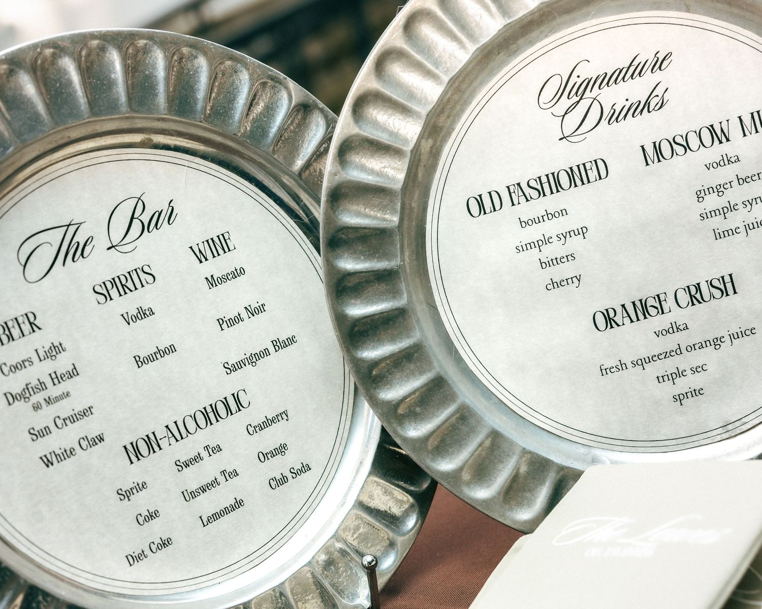 Elegant silver pie tin wedding bar menus displaying signature cocktails, spirits, wine, and non-alcoholic drink options.
