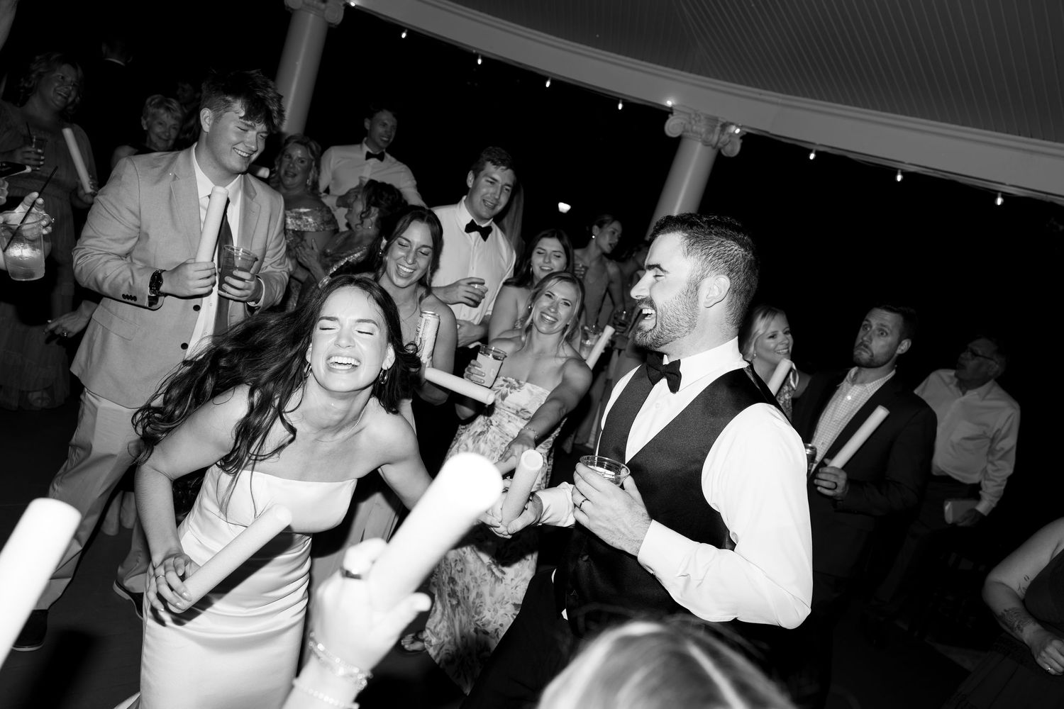 Bride and groom dancing joyfully with guests at lively wedding reception party.