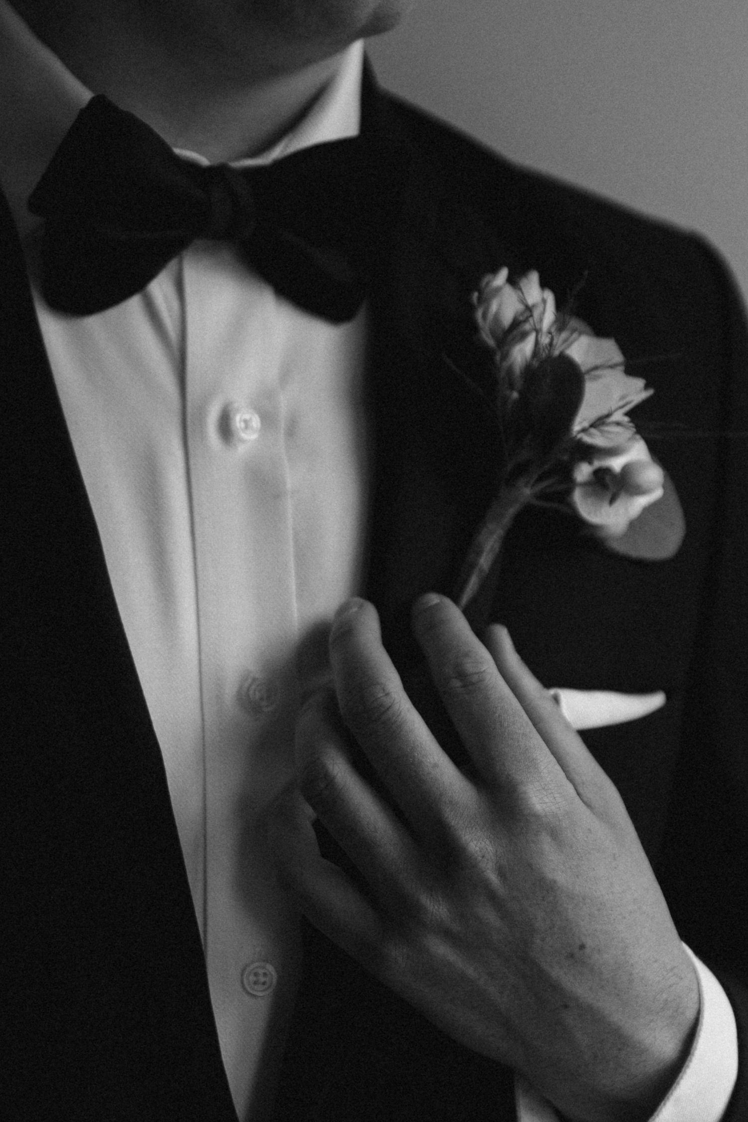 Close-up black and white detail of groom's tuxedo with floral boutonniere.