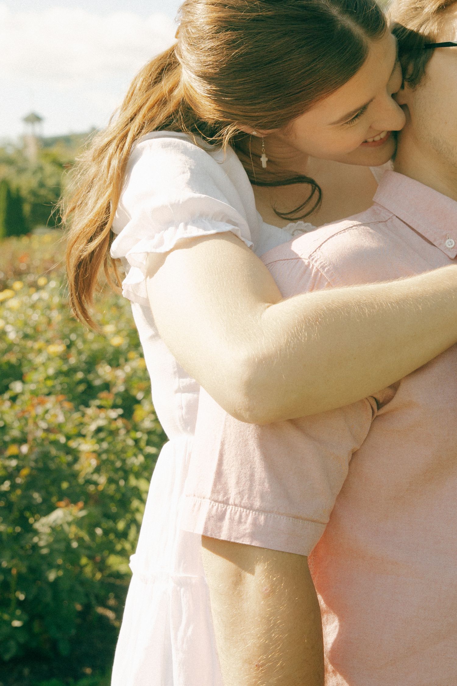 A tender embrace in warm sunlight with soft focus and dreamy lighting in a garden setting.