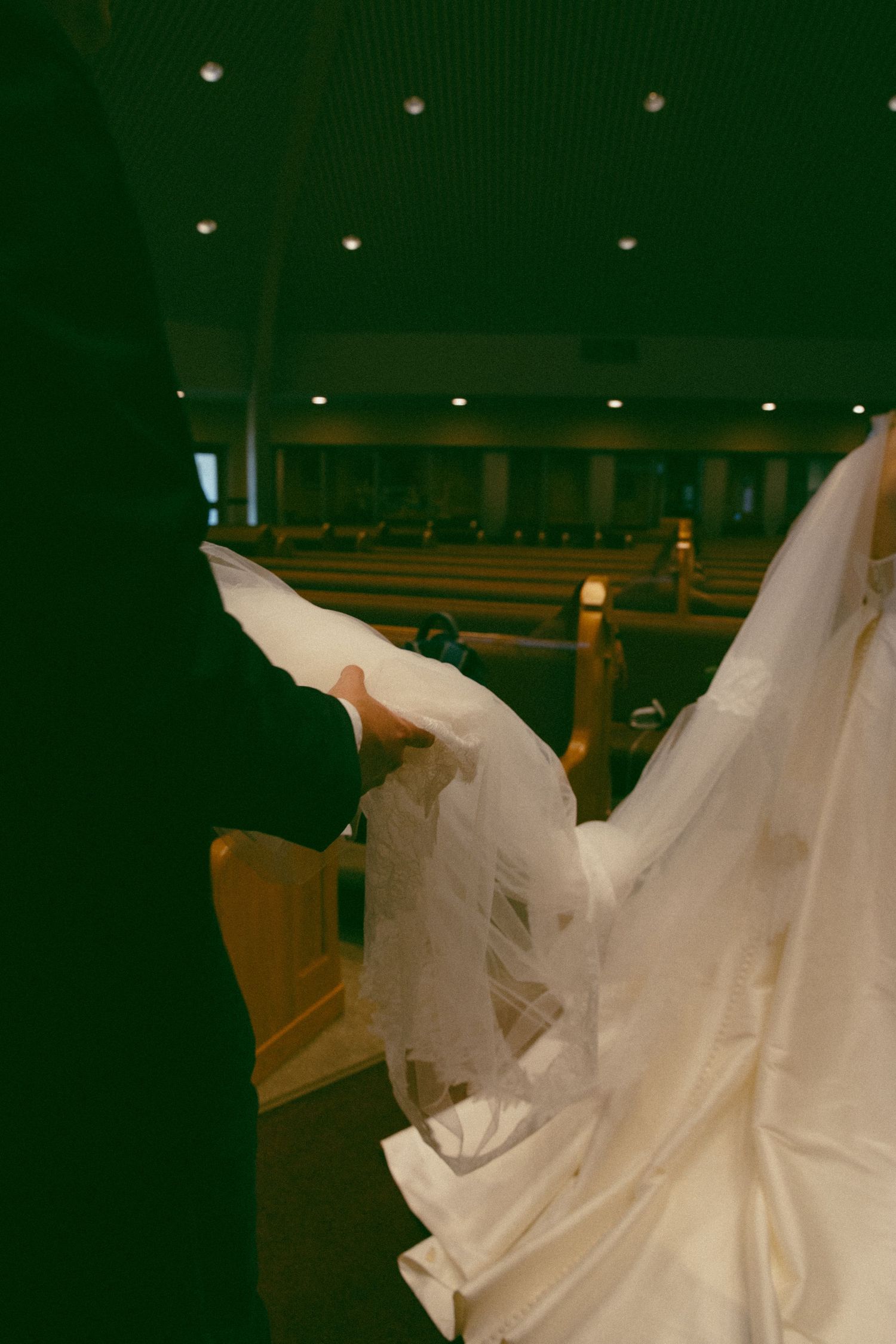 Detail shot of flowing white wedding dress fabric in dimly lit venue.