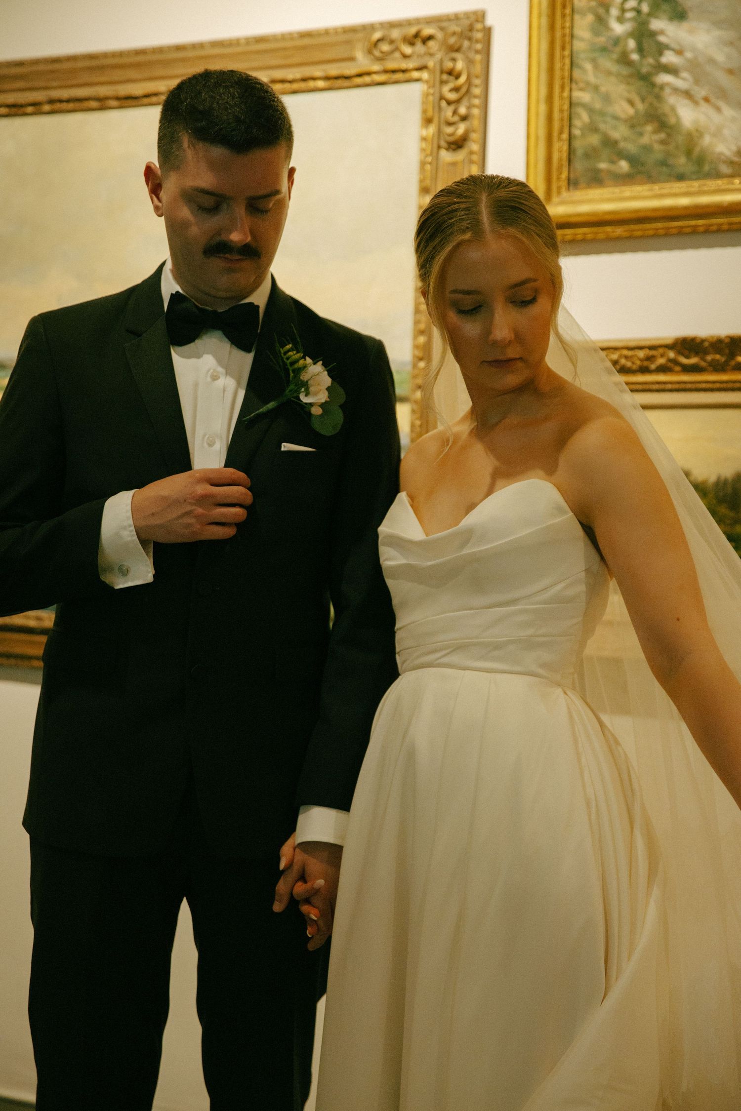 Intimate wedding portrait captured against backdrop of golden framed artwork.