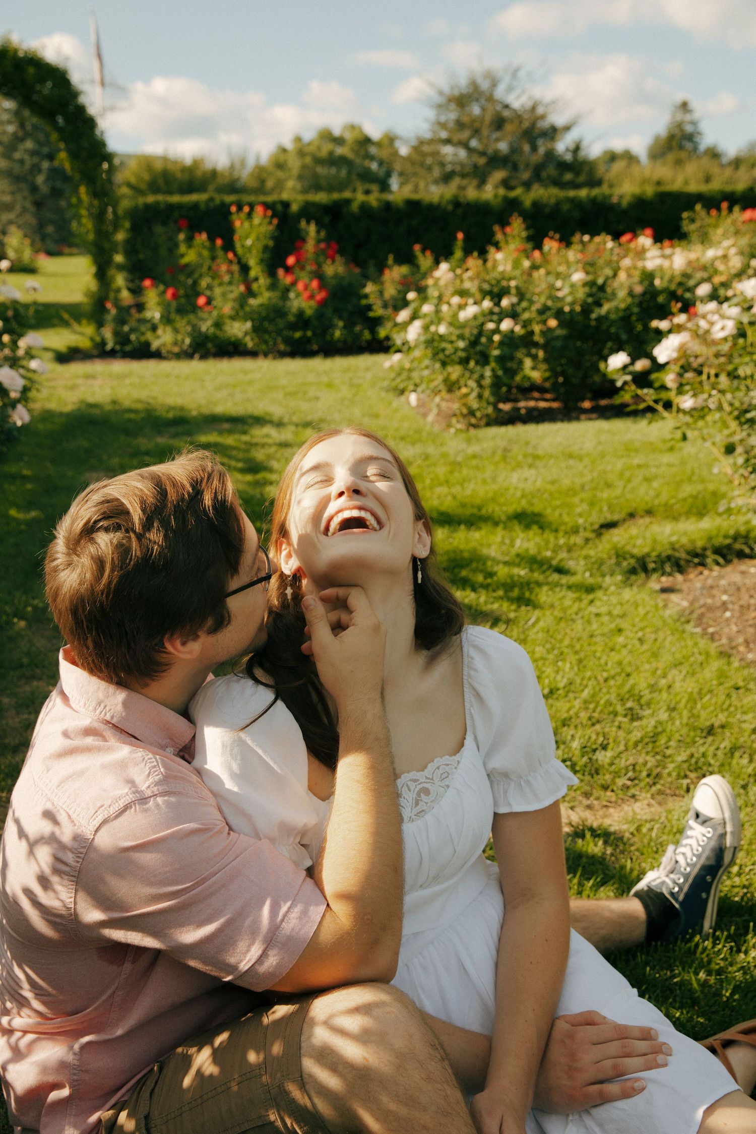 Joyful laughter captured in a sunny garden filled with white and red flowers.