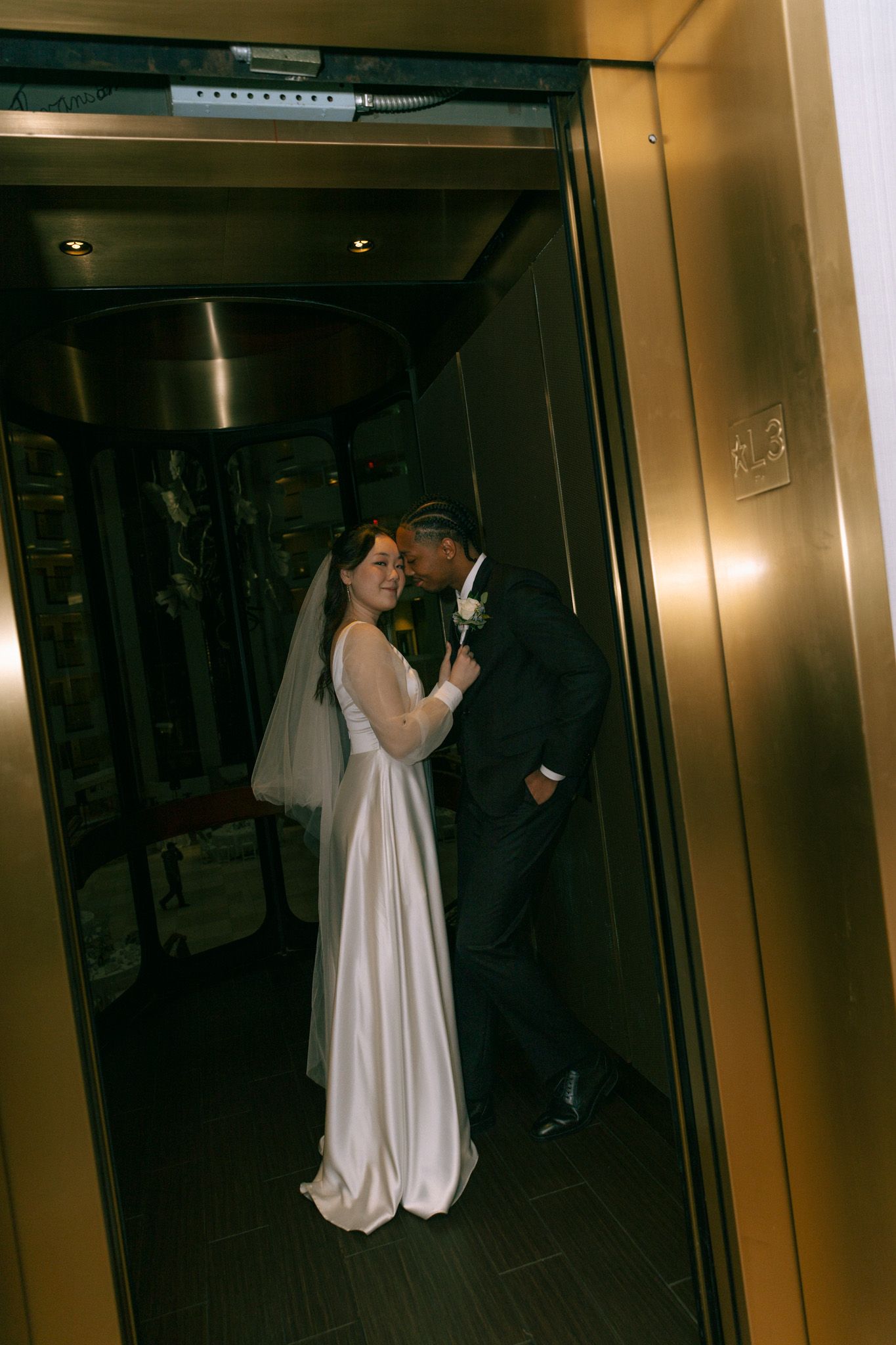 A romantic moment between newlyweds in an elevator with moody lighting.