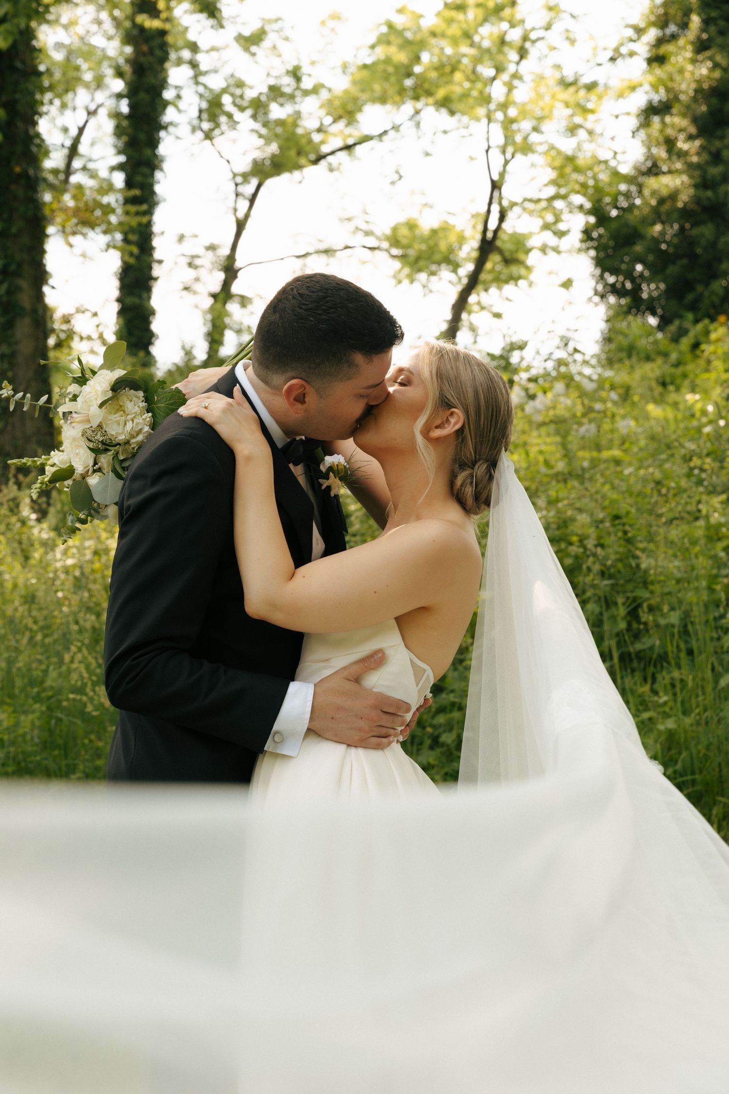 Romantic wedding moment captured in a lush garden setting with flowing white dress.