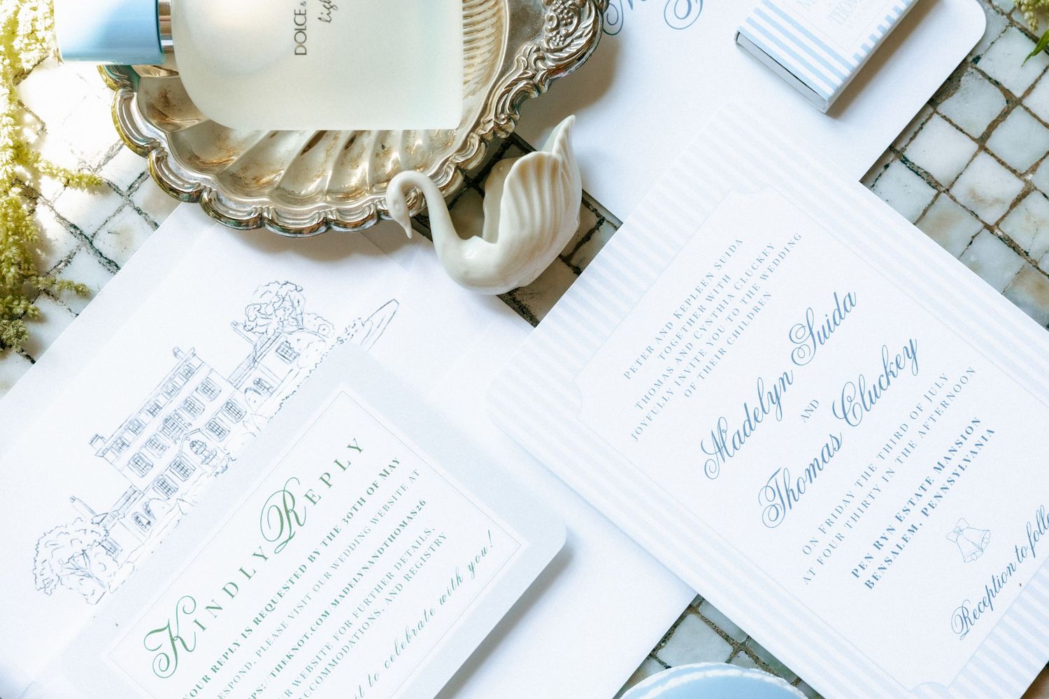 Elegant blue and white wedding stationery suite with calligraphy script, displayed on a silver tray with decorative accents.