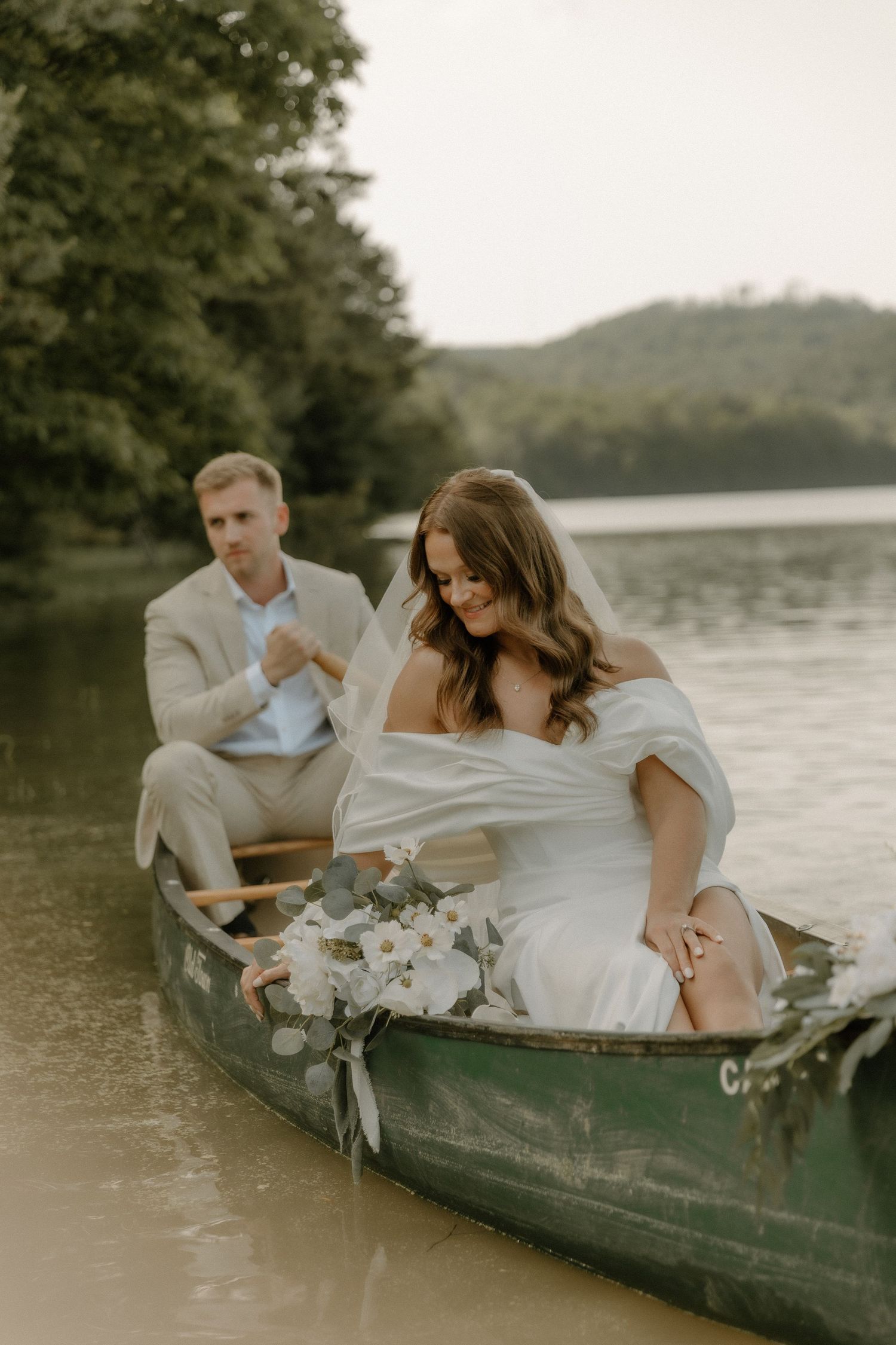 A romantic canoe engagement shoot with a couple in wedding attire on a serene lake.