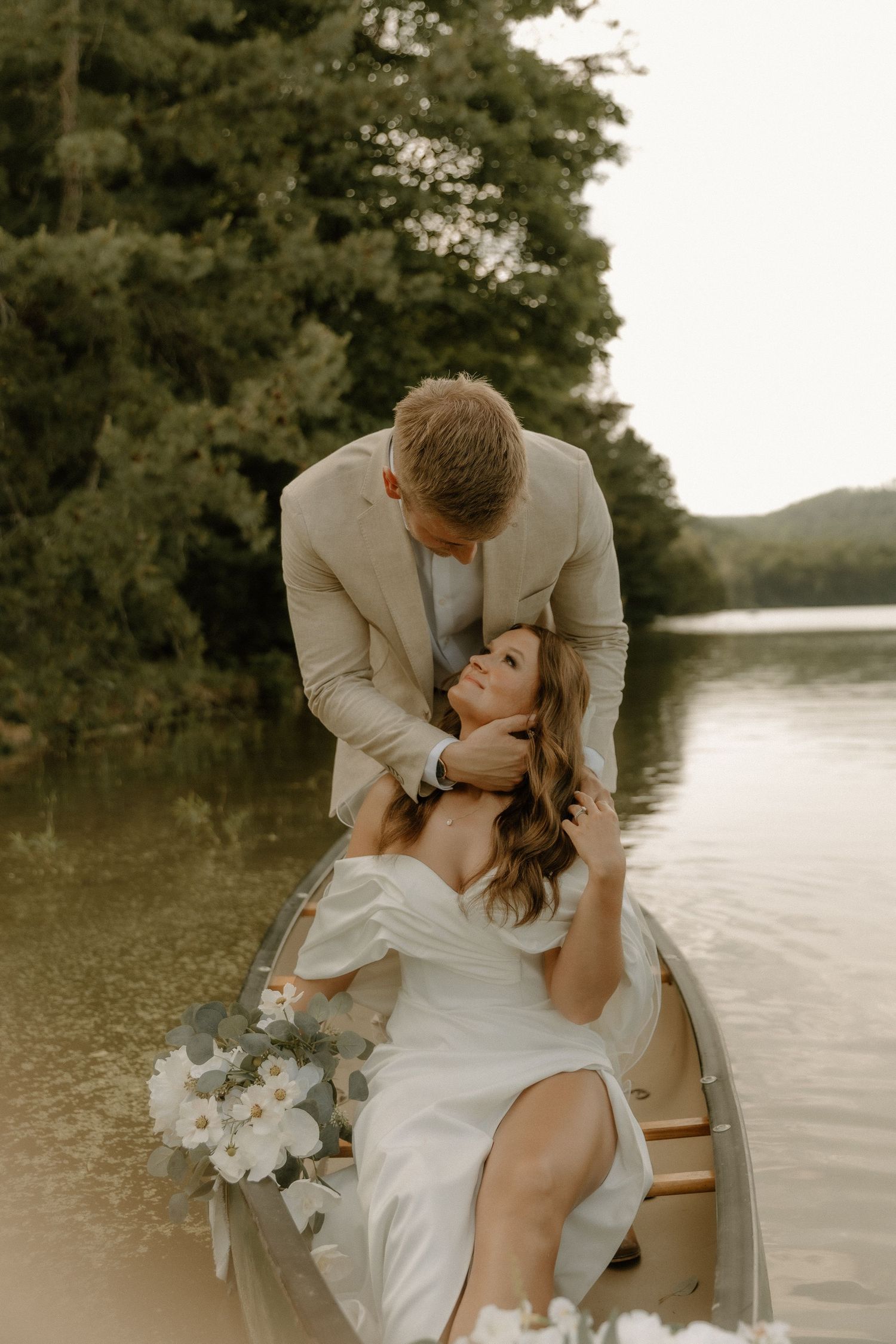 Intimate moment between newlyweds in a flower-decorated canoe on a lake.