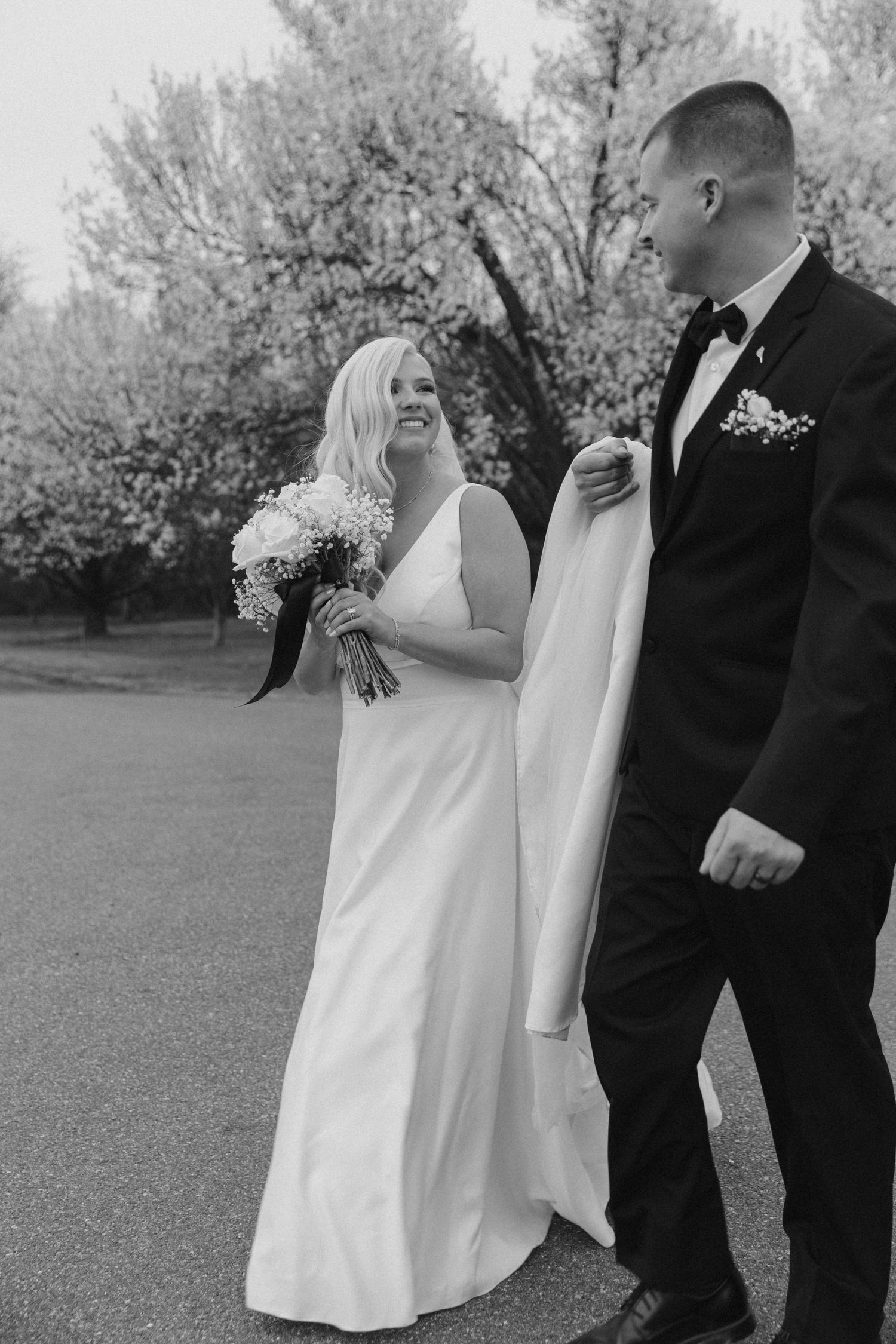 Black and white photo capturing a joyful wedding moment in an outdoor garden setting.