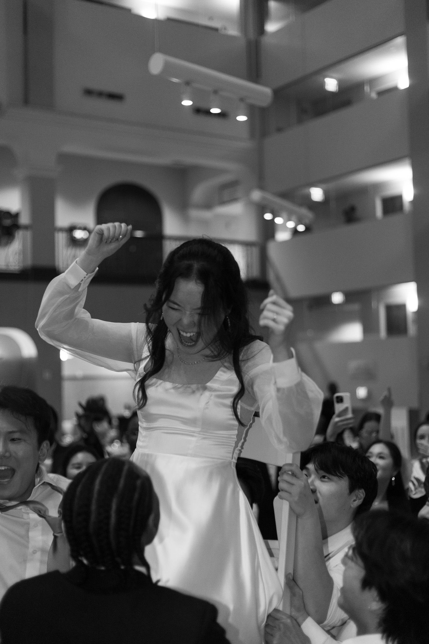 Bride celebrating with guests during wedding reception in black and white.
