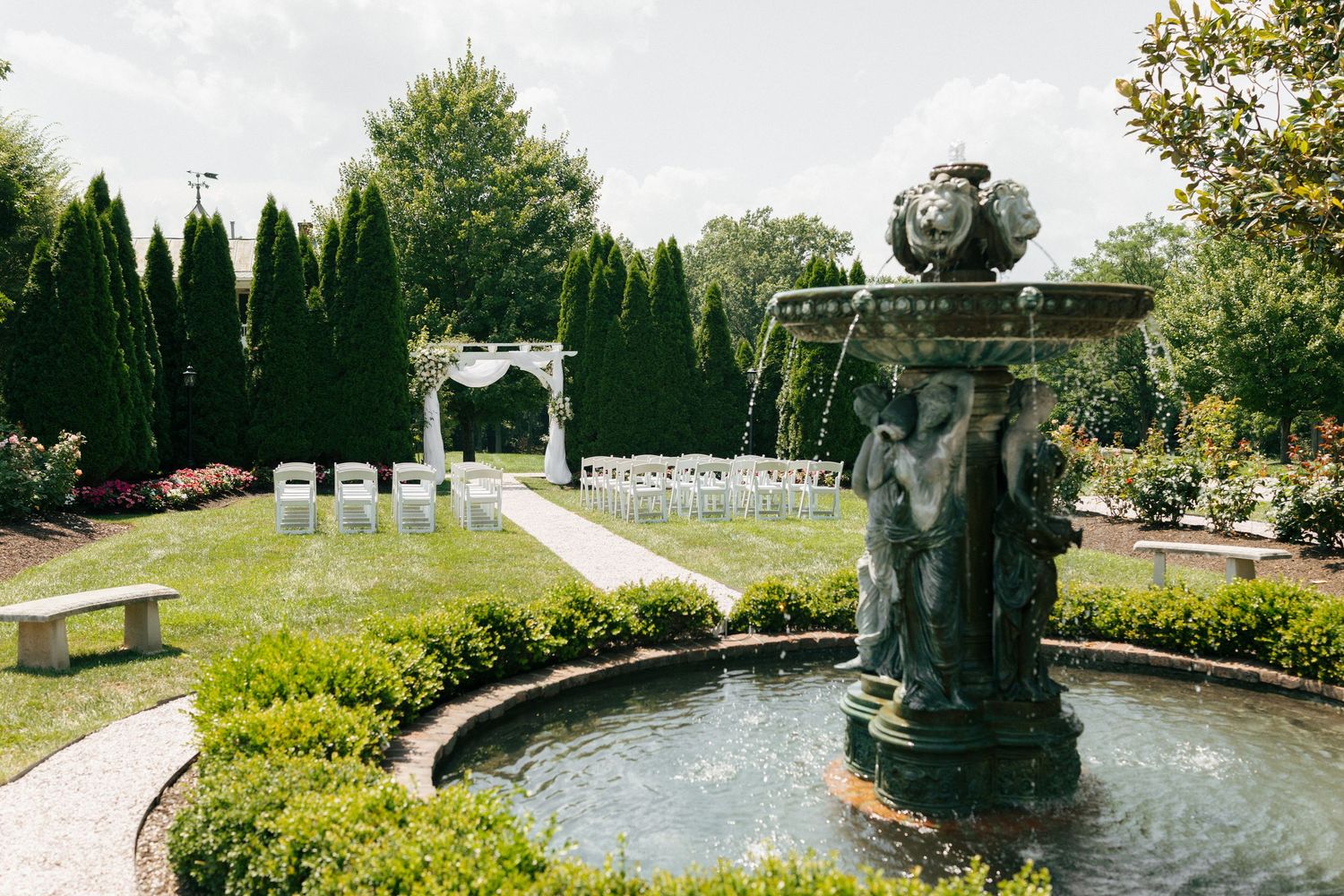 Scenic garden path leads through manicured hedges and fountains in a formal European-style landscape design.