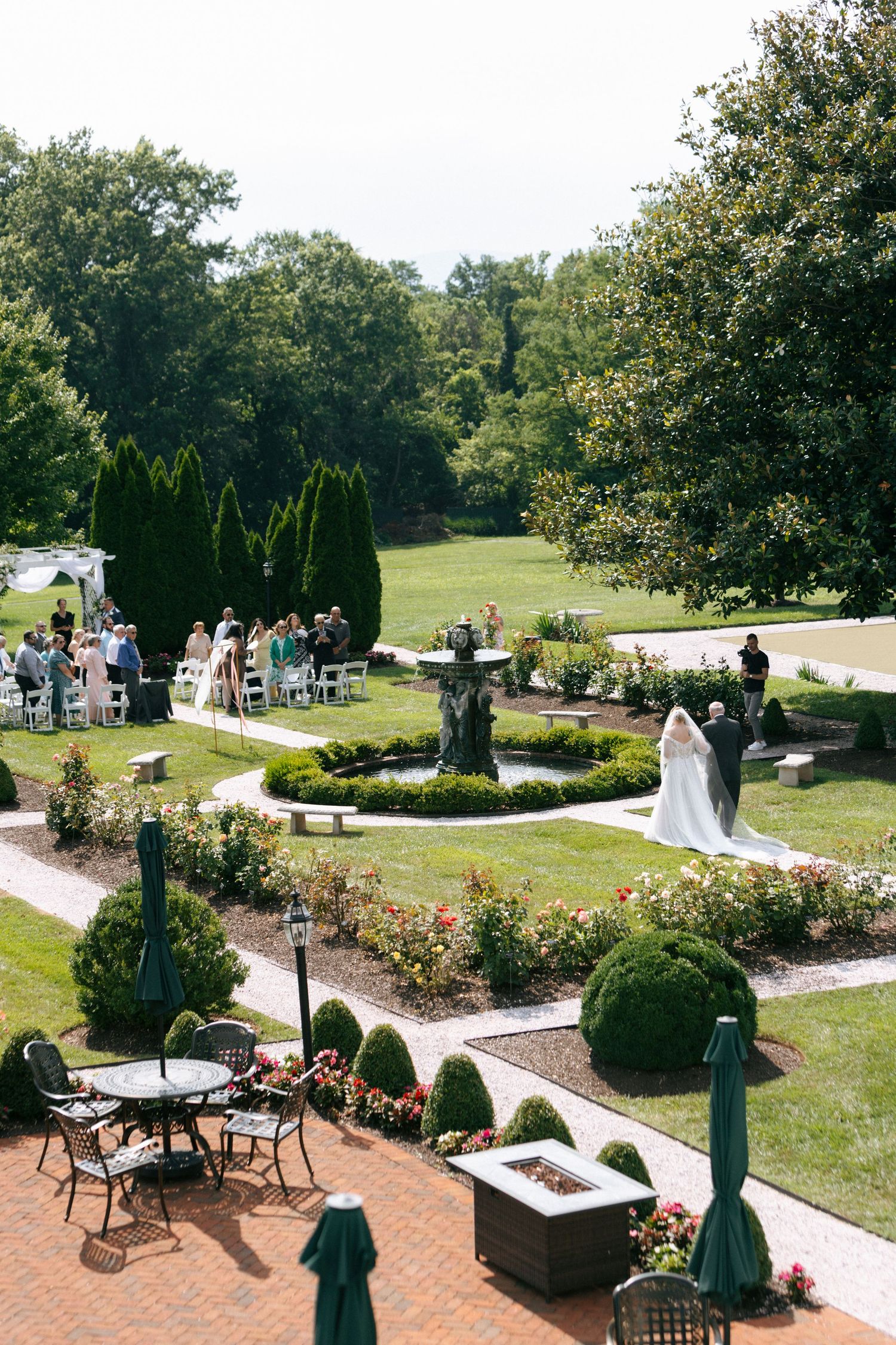 Beautiful garden wedding venue with brick pathways, manicured landscaping, and outdoor seating areas surrounded by trees.