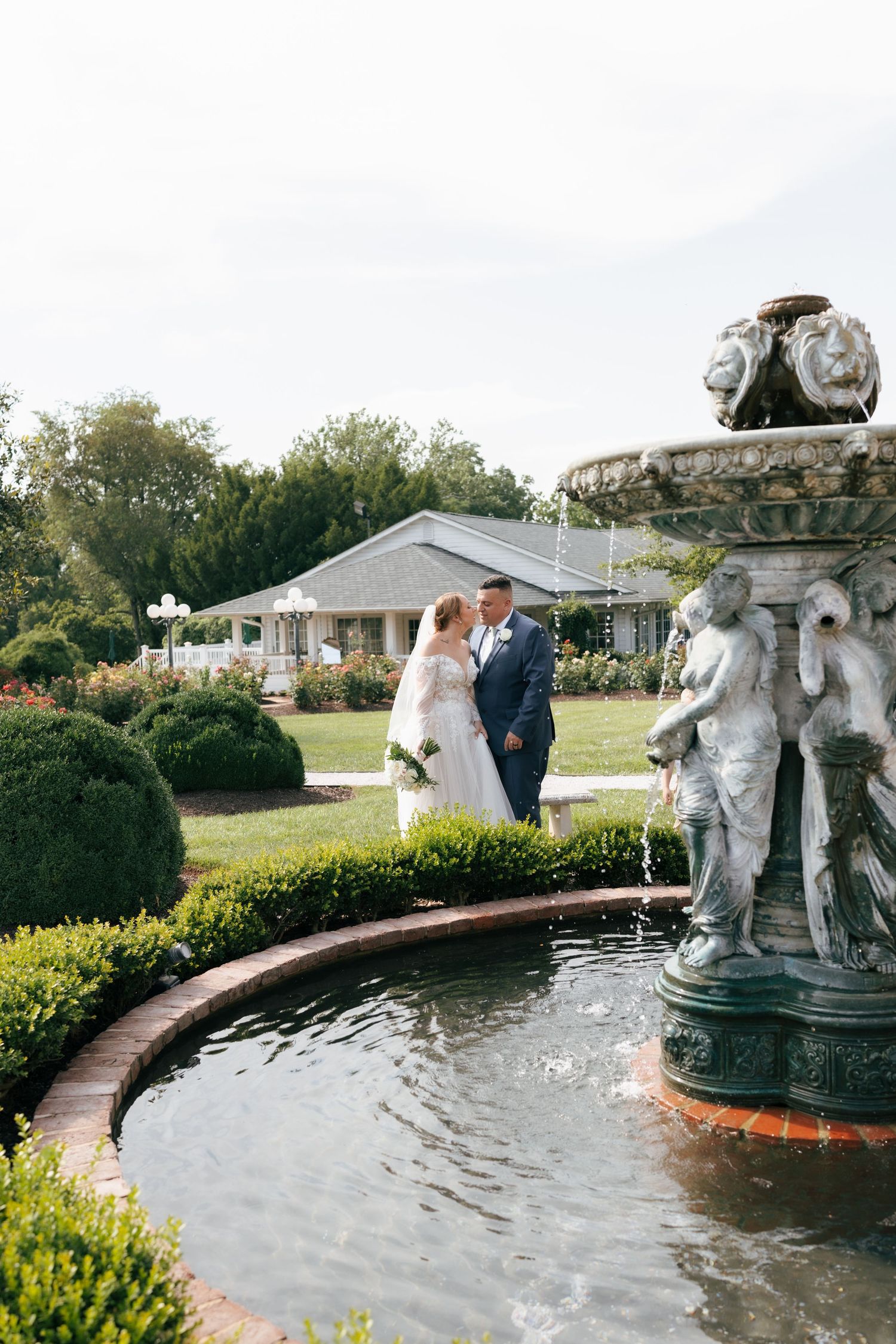 Elegant outdoor fountain with cherub statues creates a romantic backdrop in a landscaped garden setting.