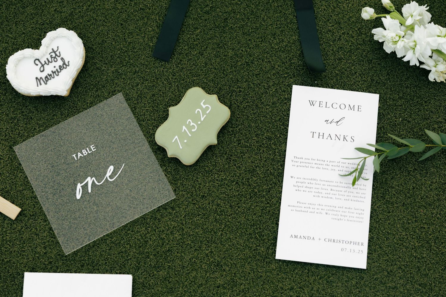 Wedding stationery and paper goods arranged on green grass including invitations, place cards, and thank you notes.