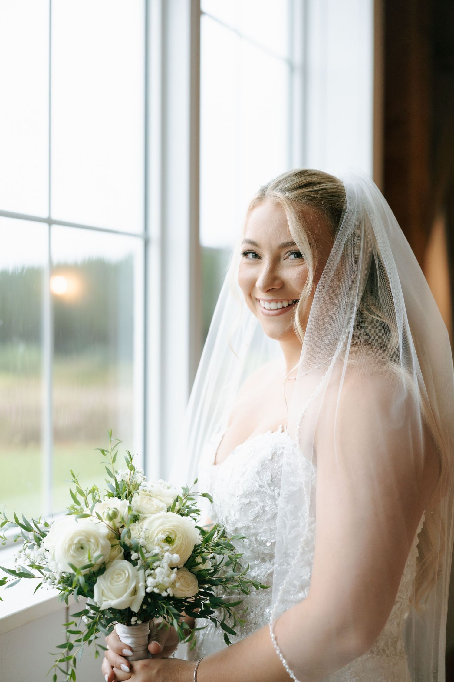 Wedding portrait sequence by large windows with natural light and white floral bouquet.